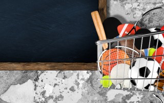shopping cart filled with sports equipment in front of stone wall with blackboard