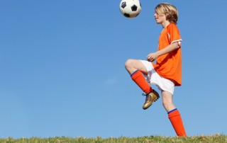 boy kid playing soccer kicking football.