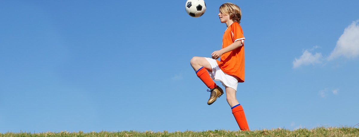 boy kid playing soccer kicking football.